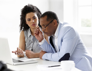 African American woman and man looking intently at laptop and discussing